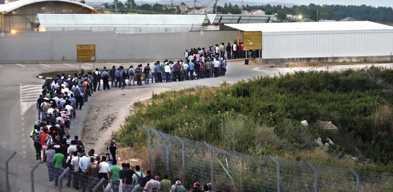 פועלים פלסטינים במעבר חשמונאים / צילום: Reuters פועלים פלסטינים במעבר חשמונאים / צילום: Reuters